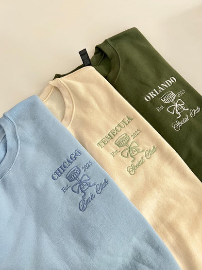 Three embroidered bridal party sweatshirts in blue, cream, and green