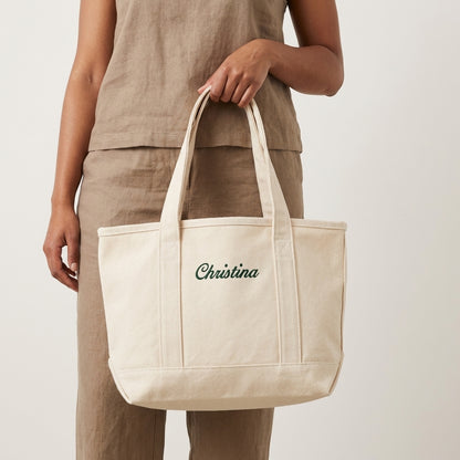Model holding a natural tote bag with Christina name embroidery