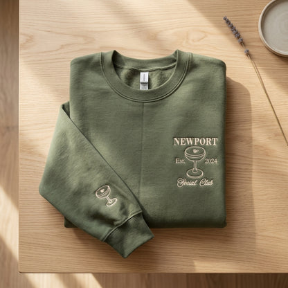 Folded green sweatshirt with front and sleeve drink glass embroidery