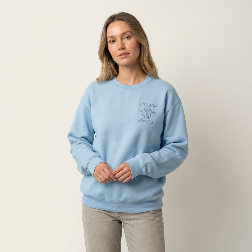 Model wearing a light blue sweatshirt with Chicago Bach Club embroidery