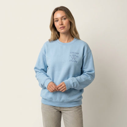 Model wearing a light blue sweatshirt with Chicago Bach Club embroidery