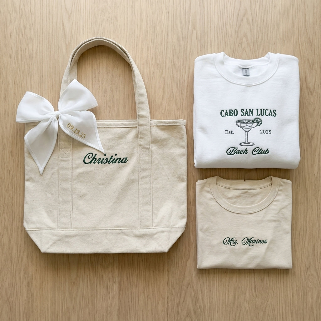 Personalized tote bag with bow beside folded embroidered shirts